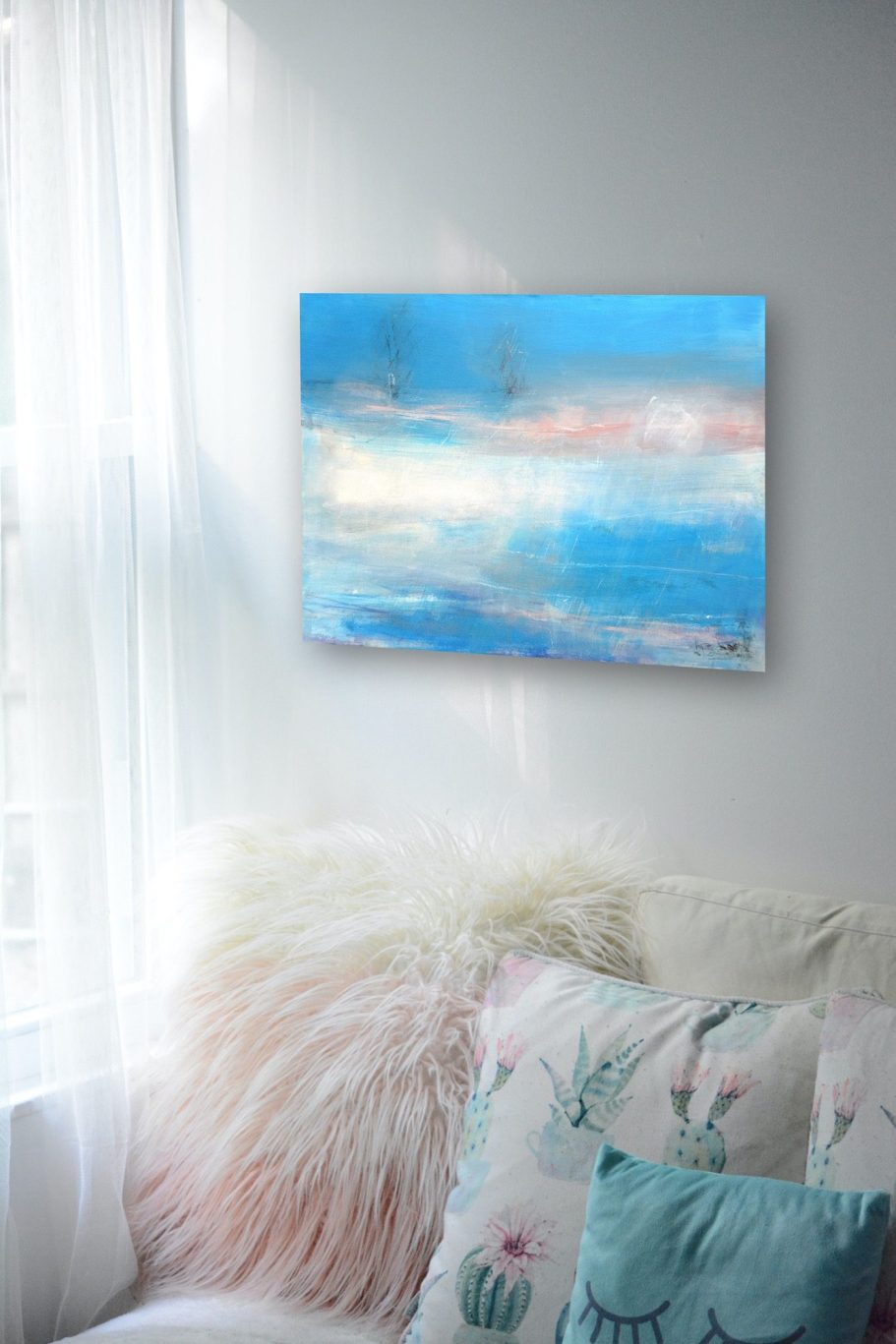 Abstrakte Malerei in Blau- und Pastelltönen an einer Wand, neben einem weißen Sofa.