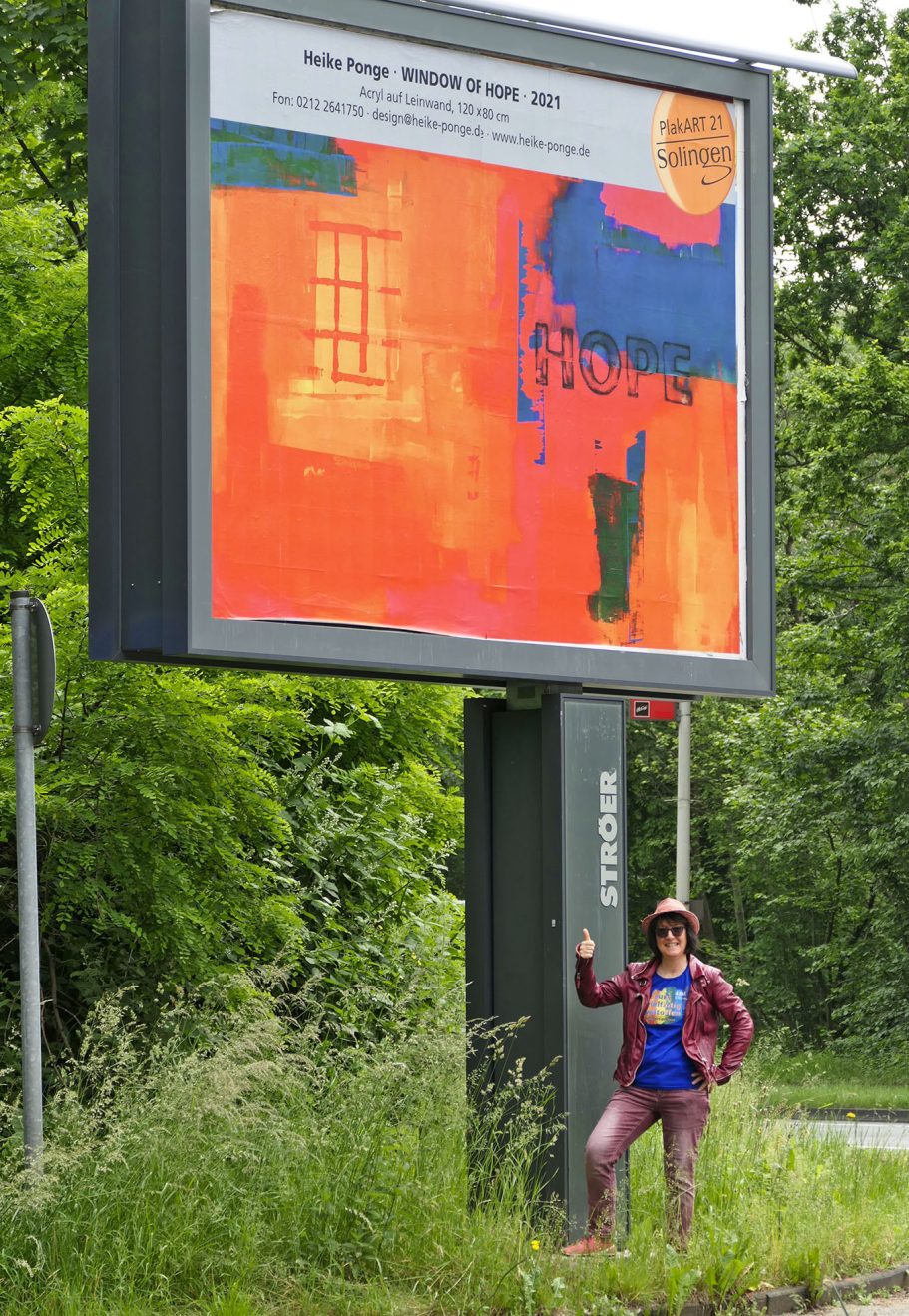 Eine Person steht vor einem großen Plakat mit kunstvollem, buntem Motiv.
